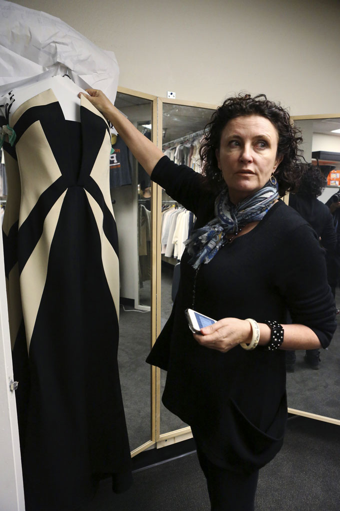 Lyn Paolo, costume designer holds a Rubin Singer gown worn by Kerry Washington in the ABC drama series, "Scandal," in the show's wardrobe closet on the Sunset Gower lot in the Hollywood section of Los Angeles.  (AP Photo/ABC, Danny Feld)