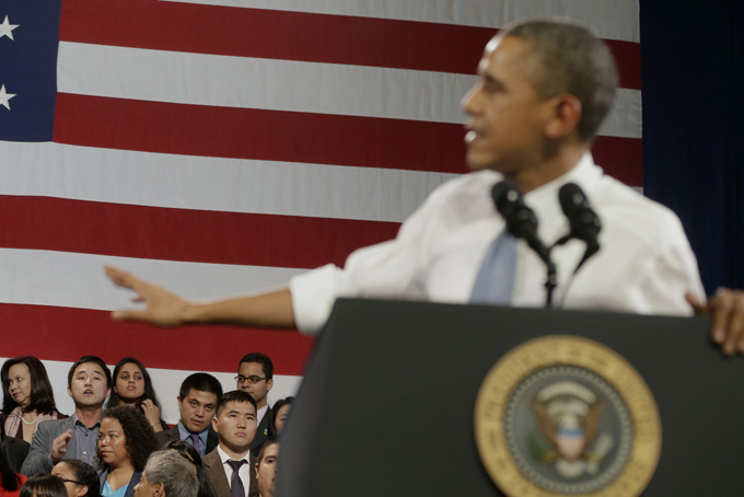 President Barack Obama, right, gestures as he attempts to respond to a unidentified man, lower left, who began to heckle him about anti-deportation policies,  Nov. 25, 2013, at the Betty Ann Ong Chinese Recreation Center in San Francisco. Obama stopped his speech about immigration reform to let this man, who was located directly behind him, speak and would respond to his questions during the event. (AP Photo/Pablo Martinez Monsivais)