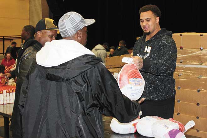 SAYING THANKS, GIVING BACK—Pittsburgh Steelers Center Maurkice Pouncey handing out Thanksgiving turkeys to those in need at his Thanksgiving Celebration Nov. 21 at Stage AE. (Photo by J.L. Martello)