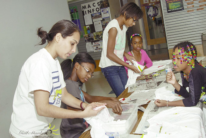 WATER PROOFING—Pitt student Snehal Sawlani examines the tee shirt of Amber Hogan, 11, during the water proofing experience, while Aniya Avery, 7, looks on. Kennede Mickley, 11, and Dominique Ross, 12,  can be seen examining their tee shirt. (Photos by Gail Manker)