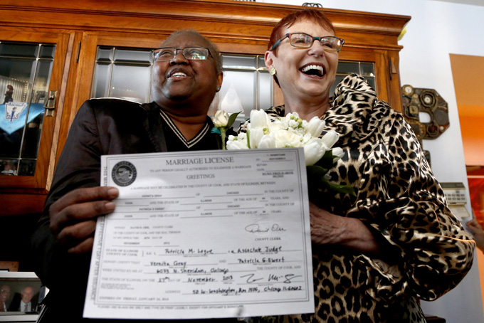 Holding their Illinois marriage license, Vernita Gray, left, and Patricia Ewert smile at friends after they were married by Cook County Judge Patricia Logue, the first gay marriage in Illinois, at the couple's home Wednesday, Nov. 27, 2013, in Chicago. (AP Photo/Charles Rex Arbogast)
