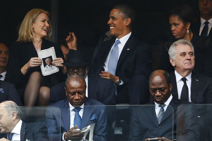 President Barack Obama jokes with Danish prime minister, Helle Thorning-Schmidt, left, as first lady Michelle Obama looks on at right during the memorial service for former South African president Nelson Mandela at the FNB Stadium in Soweto, near Johannesburg, South Africa, Tuesday Dec. 10, 2013. (AP Photo/Matt Dunham)