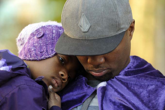 Quinton Reynolds, of Emeryville, wears a purple cape as he holds his daughter Qniyah Reynolds, 4, as he gathers with others outside of Children's Hospital Oakland in support of Jahi McMath in Oakland, Calif., on Monday, Dec. 23, 2013. (AP Photo/The Contra Costa Times-Bay Area News Group, Susan Tripp Pollard)