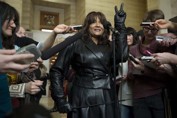 Terri-Jean Bedford gives a victory sigh as she talks to reporters at the Supreme Court of Canada in Ottawa Friday morning, Dec. 20, 2013 after learning Canada's highest court struck down the country's prostitution laws in their entirety in a unanimous 9-0 ruling. (AP Photo/The Canadian Press, Adrian Wyld)