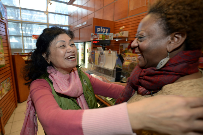 Owner Young Soo Lee, left, is congratulated by regular customer Dawn Palmerat her small Alliance Center office building newsstand on Wednesday, Dec. 18, 2013, in Atlanta, after lottery officials said one of two winning Mega Millions lottery tickets were purchased from her store in Tuesday's $636 million drawing, The store owner said she sold 1300 lottery tickets on Tuesday rather than the normal sales of about 100 tickets. (AP Photo/David Tulis)