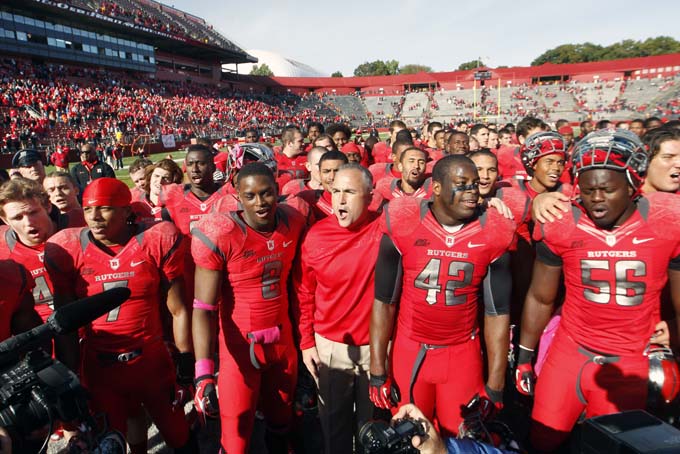 In this Oct. 13, 2012, photo, Rutgers coach Kyle Flood, center, stands with his players as they sing Rutgers' alma mater after defeating Syracuse in an NCAA college football game in Piscataway, N.J. Rutgers has gone a respectable 53-36 with six bowl appearances in football since 2007, when it dropped six sports, and attendance at High Point Solutions Stadium has averaged more than 45,000, a number that’s still short of the new seating capacity of 52,454 that came with a $102 million expansion completed in 2009. (AP Photo/Mel Evans, File)