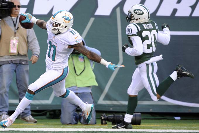 Miami Dolphins wide receiver Mike Wallace (11) celebrates after scoring a touchdown as New York Jets cornerback Kyle Wilson (20) runs behind him during the second half of an NFL football game, Sunday, Dec. 1, 2013, in East Rutherford, N.J. (AP Photo/Bill Kostroun)