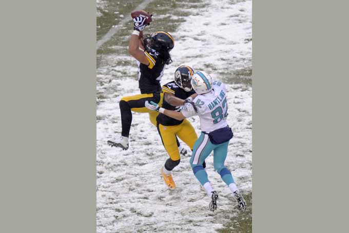 Pittsburgh Steelers strong safety Troy Polamalu , left, intercepts a pass intended for Miami Dolphins wide receiver Brian Hartline (82) and returns it for a touchdown during the second half of an NFL football game in Pittsburgh, Sunday, Dec. 8, 2013. (AP Photo/Don Wright)