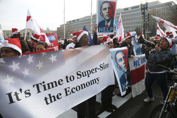 Activists, holding posters of President Barack Obama, momentarily block Independence Avenue in Washington, Thursday, Dec. 5, 2013, as they protest the minimum wage outside a McDonald's restaurant at the Smithsonian's National Air and Space Museum in Washington, Thursday, Dec. 5, 2013.  (AP Photo/Charles Dharapak)