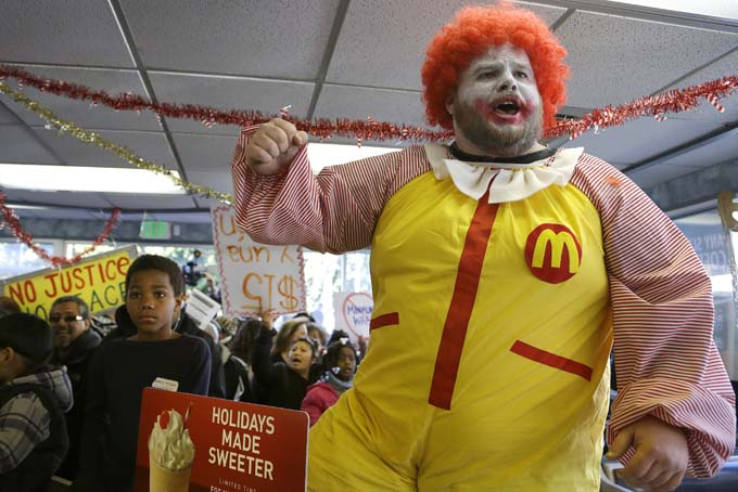 Protestors including a man dressed as Ronald McDonald chant as they take over a McDonald's restaurant Thursday, Dec. 5, 2013, in Oakland, Calif. (AP Photo/Ben Margot)