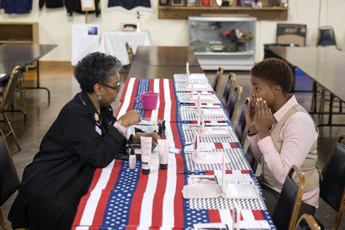 U.S Air Force Staff Sgt. Bri Smith, 31, right, of Atlanta, samples a facial moisturizer product while talking with Mary Kay consultant Asenath Holmes Pitner, left, during a job fair for veterans at the VFW Post 2681, Thursday, Nov. 14, 2013, in Marietta, Ga. Smith was looking for a job as a construction crane operator while attending the "Meal and Meet" hiring symposium and career fair co-sponsored by the Georgia Department of Labor and SolidHires. (AP Photo/David Goldman)