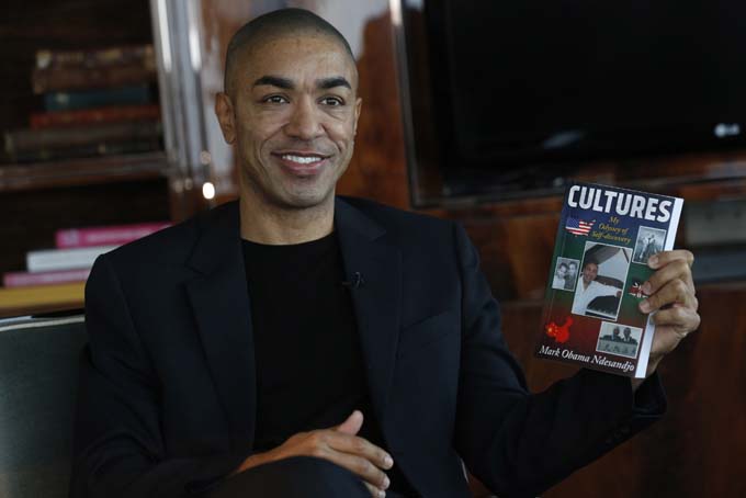 In this Dec. 17, 2013 photo, Mark Obama Ndesanjo, U.S. President Barack Obama’s half-brother, holds his self-published book “Cultures: My Odyssey of Self-Discovery” during an interview in Hong Kong. (AP Photo/Kin Cheung)