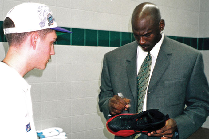 This June 11, 1997 image provided by Grey Flannel Auctions shows Michael Jordan autographing his shoes from the famous 'flu' game of the 1997 NBA Finals, for ball boy Preston Truman, left, after the Chicago Bulls played the Utah jazz in Salt Lake City. (AP Photo/Grey Flannel Auctions)