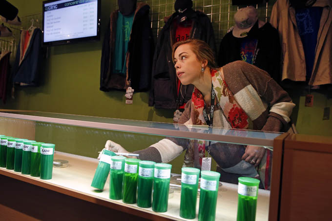 In this Dec. 6, 2013 photo, Elle Beau, an employee of The Clinic, a Denver-based dispensary with several outlets, reaches into a display case for marijuana while helping a customer, in Denver. (AP Photo/Brennan Linsley)