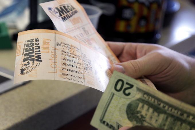 Scott Hoormann holds two Mega Millions lottery tickets he purchased at Energy Express Monday, Dec. 16, 2013, in St. Louis. (AP Photo/Jeff Roberson)