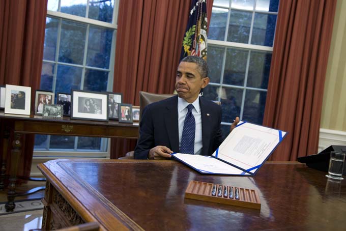 President Barack Obama closes a folder after signing the last of three bills in the Oval Office of the White House on Wednesday, Nov. 27, 2013 in Washington. (AP Photo/ Evan Vucci)