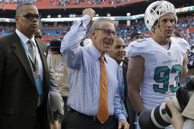 Miami Dolphins owner Stephen Ross, center, walks off the field with Dolphins outside linebacker Jason Trusnik (93) after the team defeated the New England Patriots 24-20 in an NFL football game on Sunday, Dec. 15, 2013, in Miami Gardens, Fla. (AP Photo/Lynne Sladky)