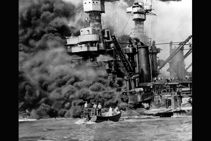 In this Dec. 7, 1941 file photo, a small boat rescues a crew member from the water as heavy smoke rolls out of the stricken USS West Virginia after the Japanese bombing of Pearl Harbor, Hawaii. Two men can be seen on the superstructure, upper center. The mast of the USS Tennessee is beyond the burning West Virginia. Saturday marked the 72nd anniversary of the attack that brought the United States into World War II. (AP File Photo)