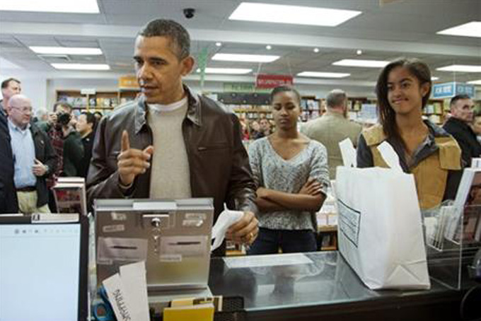 President Barack Obama, with daughters Sasha, center, and Malia, pays for his purchase the the local bookstore Politics and Prose in northwest Washington, Saturday, Nov. 30, 2013. (AP Photo/Manuel Balce Ceneta)