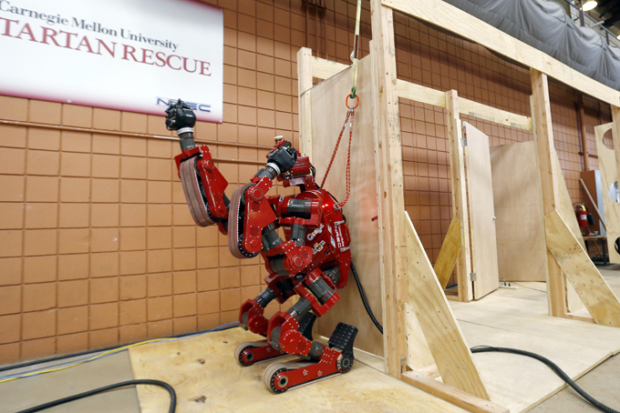 In this photo made on Wednesday, Dec. 11, 2013, the CMU Highly Intelligent Mobile Platform robot, known as CHIMP, finishes a set of doorway tests during a preparation run at the National Robotics Engineering Center in Pittsburgh. Carnegie Mellon researchers are testing the new search-and-rescue robot that will compete in the U.S. Defense Department's upcoming national robotics competition in Florida.  (AP Photo/Keith Srakocic)