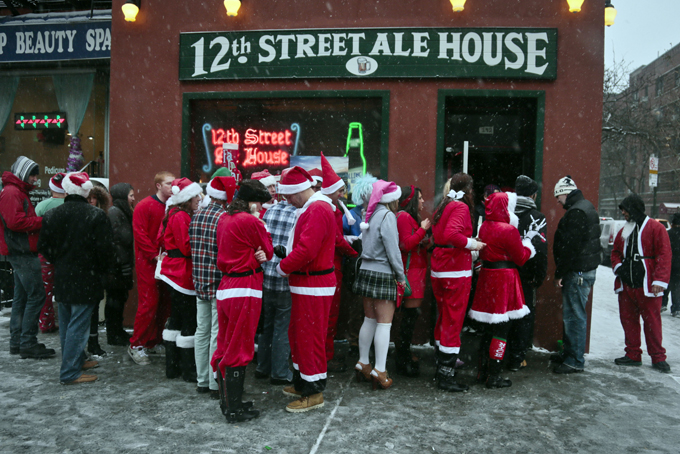 Santacon participants lineup outside a lower eastside bar on Saturday, Dec. 14, 2013 in New York. Thousands of red-suited revelers spread out through the city's bars and snowy streets amid criticism that the event has become too rowdy. (AP Photo/Bebeto Matthews)