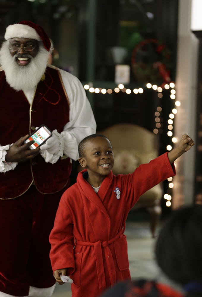 In this Tuesday, Dec. 17, 2013 photo, Dee Sinclair, who bills himself as the "Real Black Santa" smiles as Paris Allen, 7, reacts after passing a naughty or nice test in Atlanta. (AP Photo/John Bazemore)