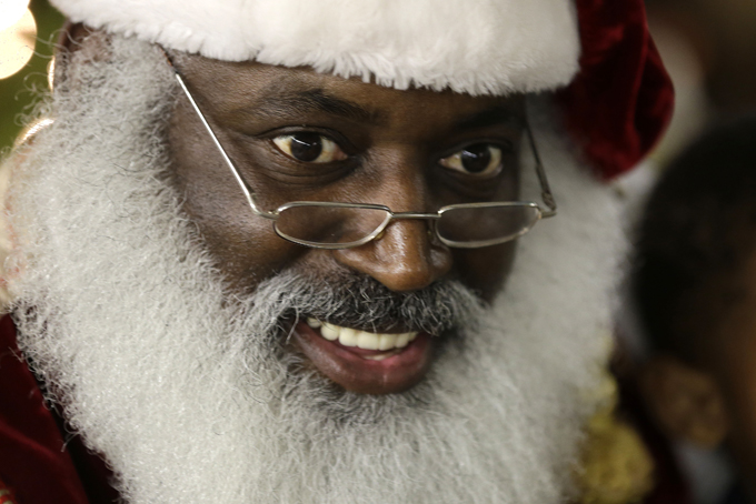 In this Tuesday, Dec. 17, 2013 photo, Dee Sinclair, portraying Santa Claus, reads a story to children in Atlanta. "Kids don't see color. They see a fat guy in a red suit giving toys," says Sinclair, 50. (AP Photo/John Bazemore)