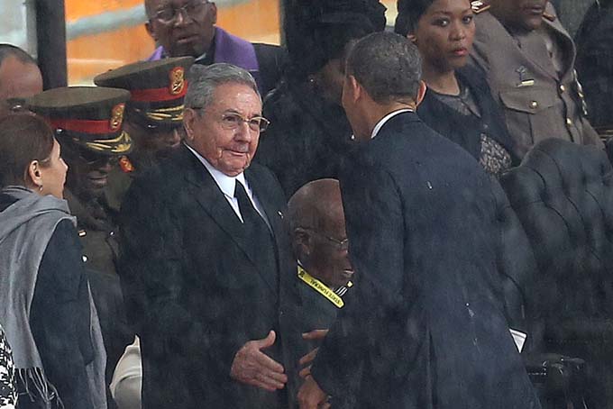 In this Tuesday Dec. 10, 2013 file photo, U.S. President Barack Obama shakes hands with Cuban President Raul Castro, as it rains during a memorial service for former South African President Nelson Mandela, at the FNB Stadium in Soweto, South Africa. (AP Photo/File)   