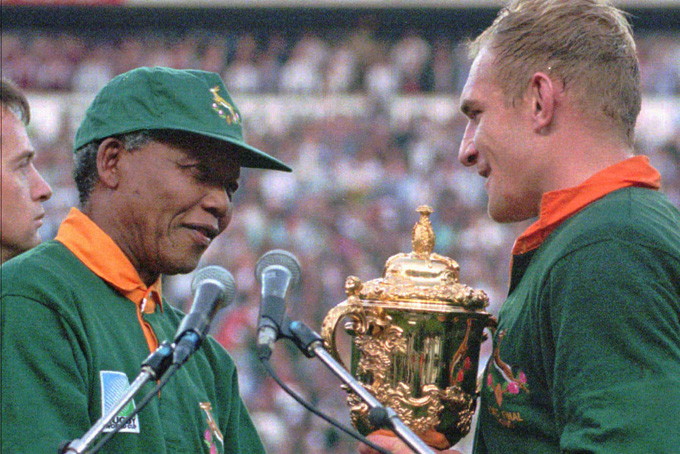 In this June 24, 1995 file photo, South African rugby captain Francios Pienaar, right, receives the Rugby World Cup from South African President Nelson Mandela, who wears a South African rugby shirt, after they defeated New Zealand in the final 15-12 at Ellis Park, Johannesburg. South Africa's President Jacob Zuma said, Thursday, Dec. 5, 2013, that Mandela has died. He was 95. (AP Photo/Ross Setford, File)