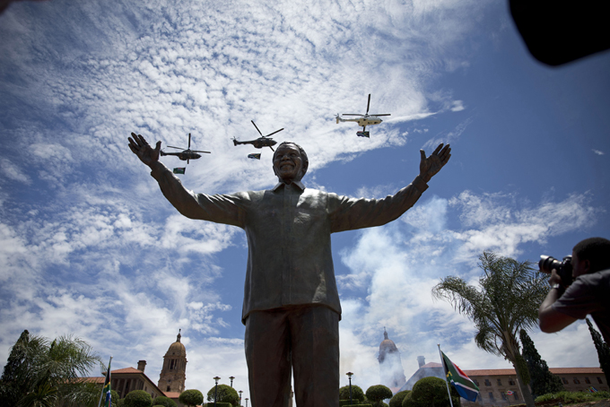 Helicopters perform a flypast as smoke rises from a gun salute after the unveiling of a 9 metre bronze statue of former South Africa President Nelson Mandela outside Union Buildings in Pretoria, South Africa, Monday, Dec. 16, 2013. The statue was unveiled as part of the Day of Reconciliation Celebrations which occur annually on December 16 at the Union Buildings, which this year fall on the structure's centenary. (AP Photo/Matt Dunham)