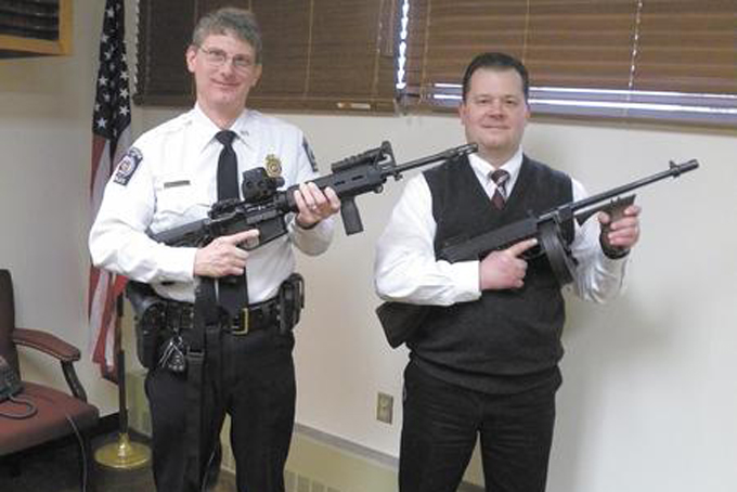 Sharon police Chief Mike Menster, right, holds a Thompson submachine gun the department has had since the 1930s. The historic gun was once favored by gangsters and used by the military. Its magazine held 50 45-caliber bullets. Set on automatic, the gun’s full magazine could be emptied with one pull of the trigger. Lt. Gerald Smith holds a Smith and Wesson Military and Police AR-15 more suited for law enforcement purposes than the Tommy gun. (Courtesy Photo/Sharon Herald)