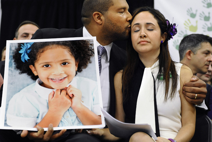 Jimmy Greene, left, kisses his wife Nelba Marquez-Greene as he holds a portrait of their daughter, Sandy Hook School shooting victim Ana Marquez-Greene at a news conference at Edmond Town Hall in Newtown, Conn., Monday, Jan. 14, 2013. (AP Photo/Jessica Hill, File)