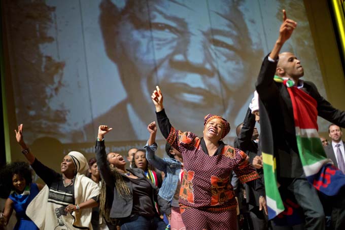 In this Wednesday, Dec. 11, 2013 file photo, members of Atlanta's South African community sing and dance under an image of former South African President Nelson Mandela during a memorial vigil in Mandela's honor at Morehouse College in Atlanta. (AP Photo/David Goldman)
