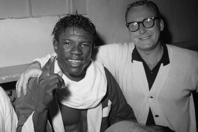 FILE - In this June 8, 1963 file photo, Emile Griffith smiles in the dressing room after regaining his welterweight world championship title by defeating Luis Rodriguez, at New York’s Madison Square Garden. At right is Griffith's coach, Gil Clancy. Griffith and fellow boxer Ken Norton were among the notables in sports who died in 2013. (AP Photo/File)