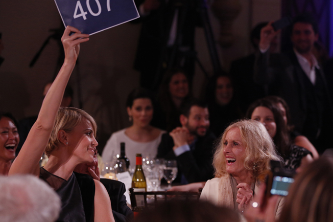 Charlize Theron, left, is seen bidding during the auction at the 3rd Annual Sean Penn & Friends HELP HAITI HOME Gala on Saturday, Jan. 11, 2014 at the Montage Hotel in Beverly Hills, Calif. (Photo by Colin Young-Wolff /Invision/AP)