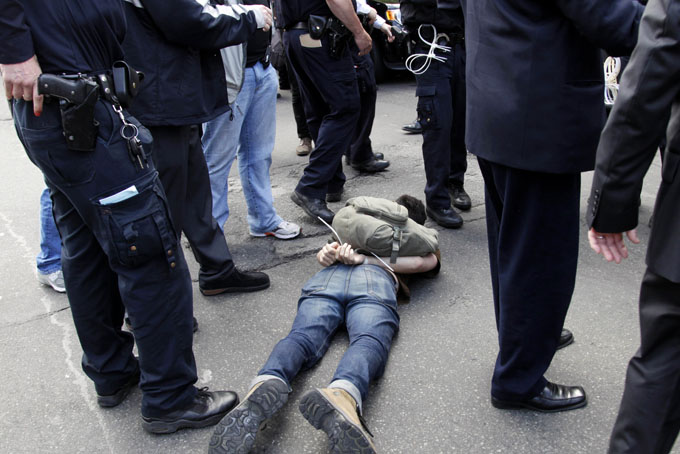 In this May 1, 2012, file photo, police officers stand around a protester who was arrested in New York. (AP Photo/Seth Wenig, File)