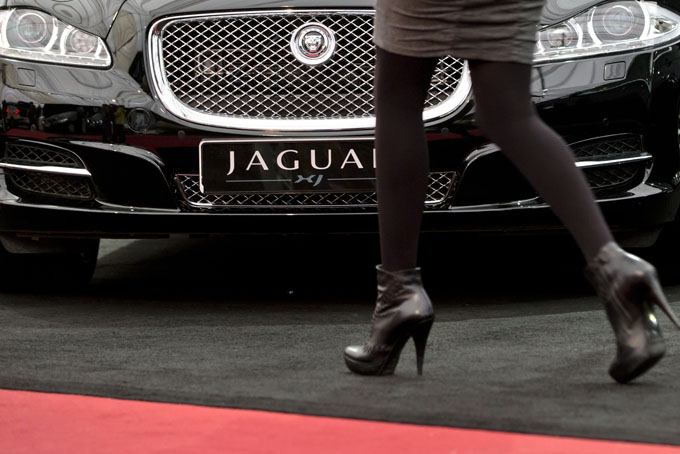 In this Wednesday, April 3, 2013, file photo, a woman passes by a Jaguar XJ during an Auto Moto Show in Bucharest, Romania. (AP Photo/Vadim Ghirda, File)