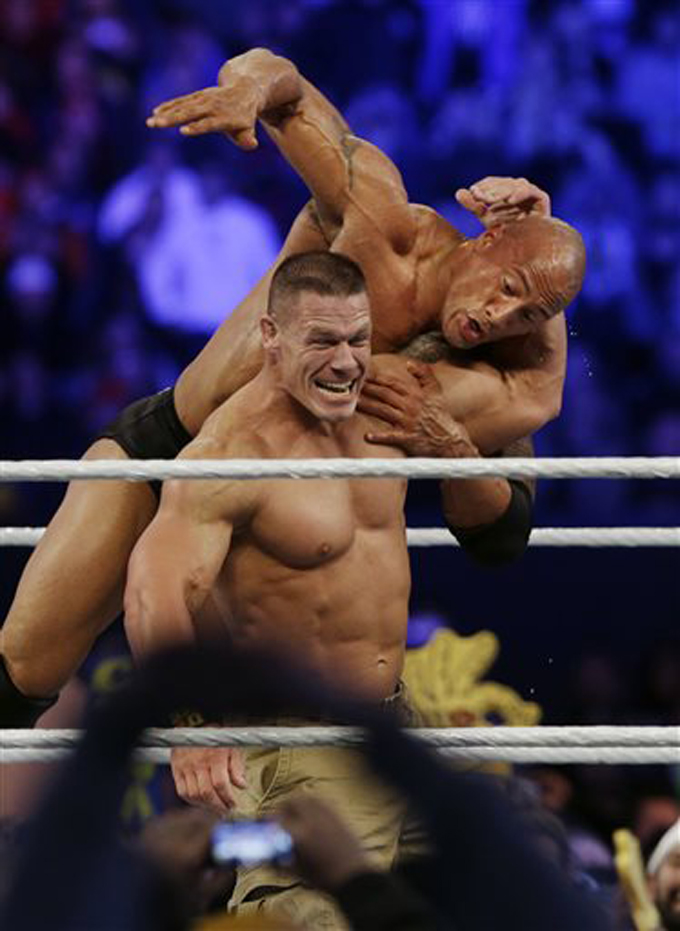 In this April 7, 2013 file photo, John Cena, left, wrestles with Dwayne Johnson, known as The Rock during Wrestlemania in East Rutherford, N.J. Johnson said he won’t rule out a return to the ring that made him famous. "I'd like to leave it open. But if I'd never wrestle again, I'd be very content with that," Johnson said recently while on set filming the season finale of TNT's "The Hero." (AP Photo/Mel Evans, File)