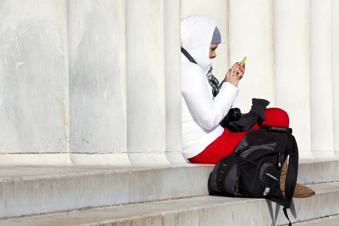 Bundled up against the cold, Maria Bayona, of Bogota, Colombia, checks her cell phone as she waits for a friend to finish their visit at the Lincoln Memorial in Washington, Jan. 4. (AP Photo/Jacquelyn Martin)