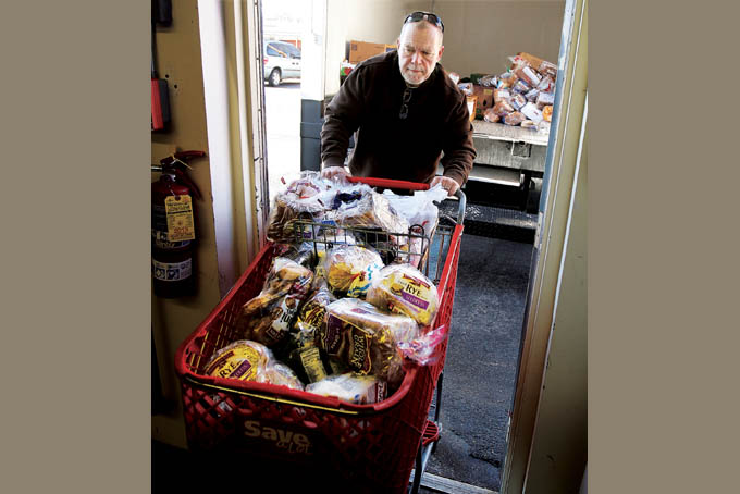 Volunteer Greg Harris pushes a basket of bread into the Guardian Angel Pantry at Catholic Charities in Alton, Ill., Tuesday, Dec. 31, 2013. Federal benefit cuts to programs like SNAP, the Supplemental Nutrition Assistance Program, have left area food pantries with more people in need. (AP Photo/The Telegraph, John Badman) 