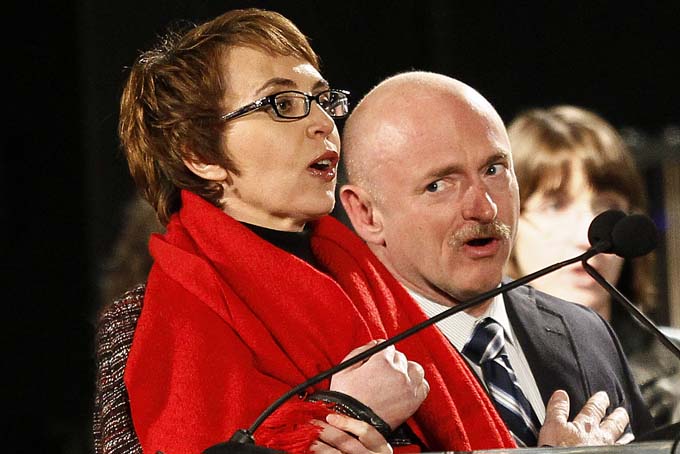 Rep. Gabrielle Giffords, left, leads the Pledge of Allegiance accompanied by her husband, former astronaut Mark Kelly, at the start of a one year memorial vigil for the victims and survivors of the shooting that wounded Giffords, 12 others and killed six in this Sunday, Jan. 8, 2012 file photo taken in Tucson, Ariz.  (AP Photo/Matt York, File)