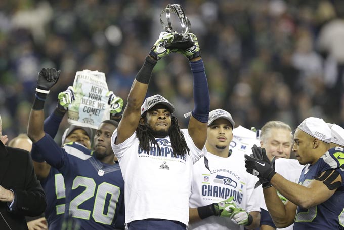 Seattle Seahawks' Richard Sherman holds up the George Halas Trophy after the NFL football NFC Championship game against the San Francisco 49ers Sunday, Jan. 19, 2014, in Seattle. The Seahawks won 23-17 to advance to Super Bowl XLVIII. (AP Photo/Elaine Thompson)