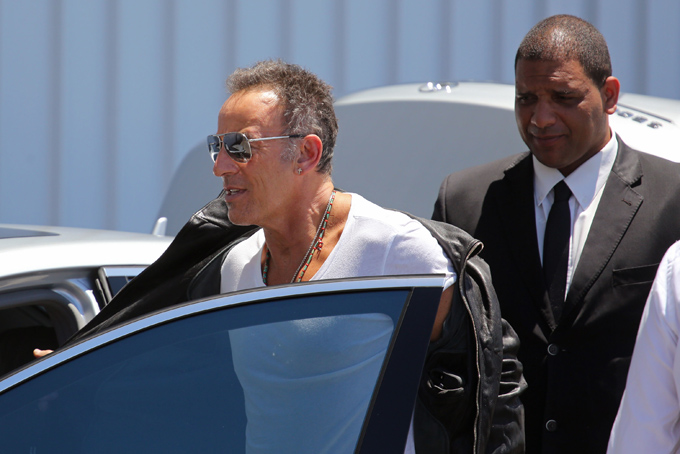 Bruce Springsteen, center, removes his jacket as he arrives at the airport in Cape Town, South Africa, Friday, Jan. 24, 2014. (AP Photo/Schalk van Zuydam)