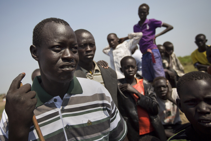 In this photo taken Thursday, Jan. 2, 2014, Phillip Madol, 33, left, one of the thousands who fled the recent fighting between government and rebel forces in Bor by boat across the White Nile, speaks to a reporter in the town of Awerial, South Sudan. (AP Photo/Ben Curtis)