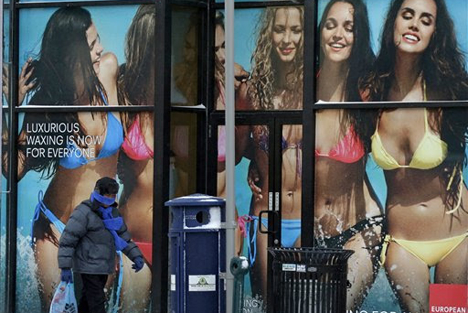 A person bundled up against the -5 degree temperatures in Pittsburgh on Tuesday morning, Jan. 7, 2014, walks past a store front advertising a European Wax Center. A high of 2 degrees is called for Tuesday in Pittsburgh. (AP Photo/Gene J. Puskar)