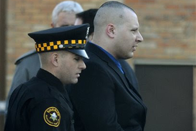 In a Nov. 13, 2013, photo Kenneth Konias is escorted by a police officer in Pittsburgh away from the Garda armored car where Michael Haines was found dead. (AP Photo/Pittsburgh Post-Gazette, Julia Rendleman) 