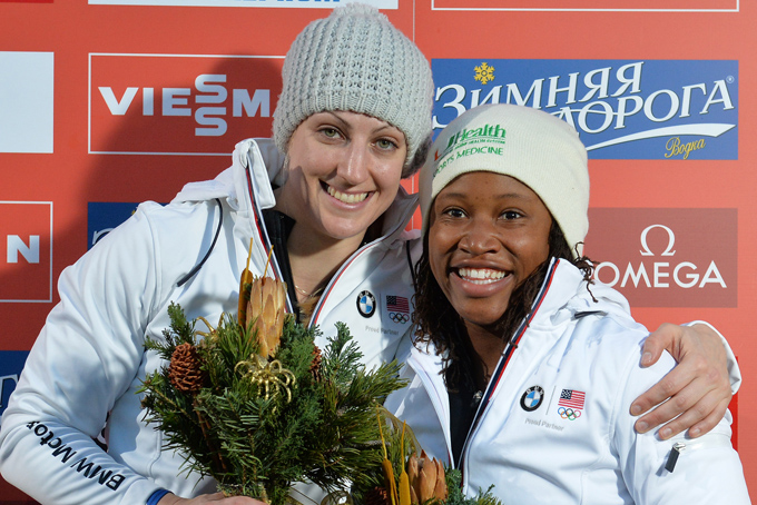 Jamie Greubel, left, and Lauryn Williams of the United States celebrate on the podium after winning the two-women Bob World Cup race in Innsbruck, Austria, on Sunday, Jan. 19. 2014. (AP Photo/Kerstin Joensson)