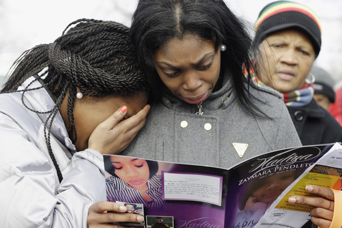 FILE - In this Feb. 9, 2013 file photo, Danyia Bell, 16, left, and Artureana Terrell, 16, react as they read a program after the funeral service for 15-year-old Hadiya Pendleton outside the Greater Harvest Missionary Baptist Church in Chicago. Hundreds of mourners and dignitaries including first lady Michelle Obama packed the funeral service for the Chicago teen whose killing catapulted her into the nation's debate over gun violence. Since her death, the number of homicides and other violent crimes that turned Chicago into a national symbol of gun violence have fallen sharply after the city and police changed strategies. (AP Photo/Nam Y. Huh, File)