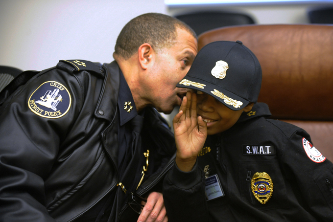 Detroit Police Chief James Craig whispers in the ear of Jayvon Felton, 9, after Felton was named Chief for A Day by Craig, at Detroit Public Safety Headquarters in Detroit on Friday Jan. 31, 2014. Felton, 9, was diagnosed with acute lymphoblastic leukemia in April. (AP Photo/Detroit News, David Coates) 