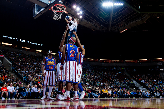 Harlem Globetrotters hoist up a young fan to make a basket during their "Fans Rule" World Tour, Monday, Feb. 17, 2014, at KeyArena in Seattle, Wash. The kid-friendly Globetrotters have thrilled families and millions of fans for 88 years. (AP Photo/seattlepi.com, Jordan Stead)